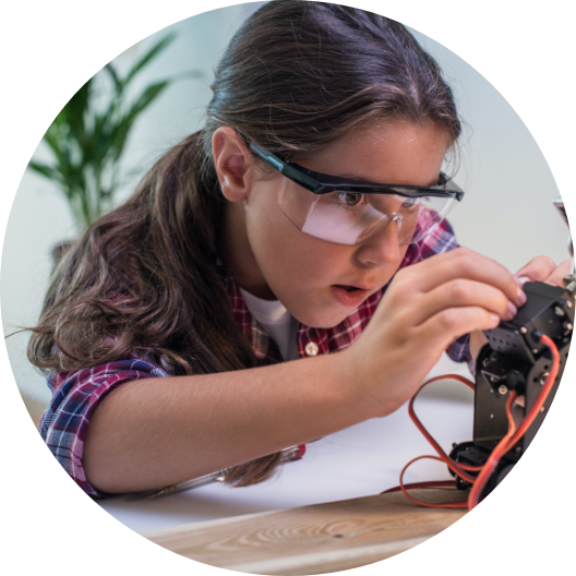 young girl wearing safety goggles and working on an electronic device 